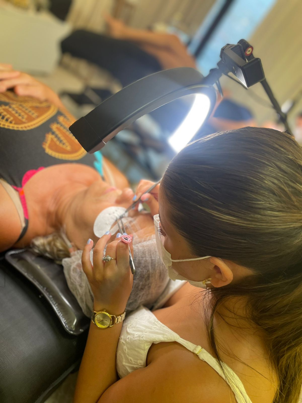 Julia aplicando extensão de cílios em cliente